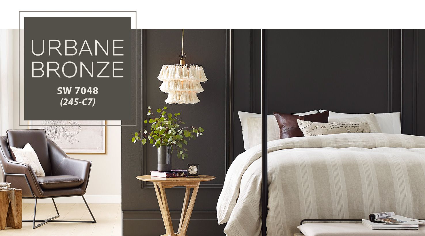 Sherwin Williams Urbane Bronze 2021 Color of the Year.  Image with Urbane Bronze accent wall behind a neutral striped bed.