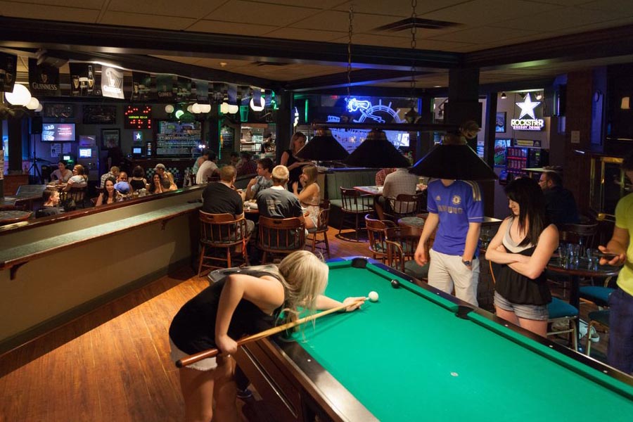 People drinking, socializing, and playing pool at O'Flannigan's pub in Kelowna