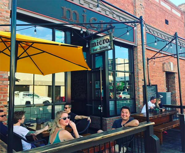 People smiling and enjoying drinks on the outdoor patio at Micro Bar in Kelowna.