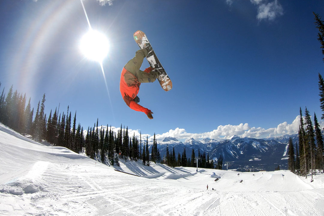 A snowboarder catching air and doing a rodeo 720 off a sick kicker in the park.