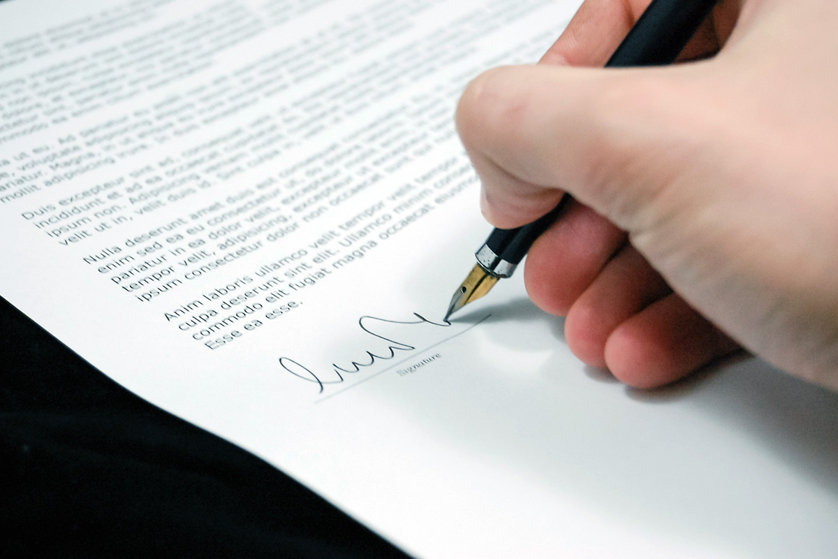 A human hand signing a contract of LOREM IPSUM with a very fancy - and I mean REALLY REALLY fancy fountain pen.