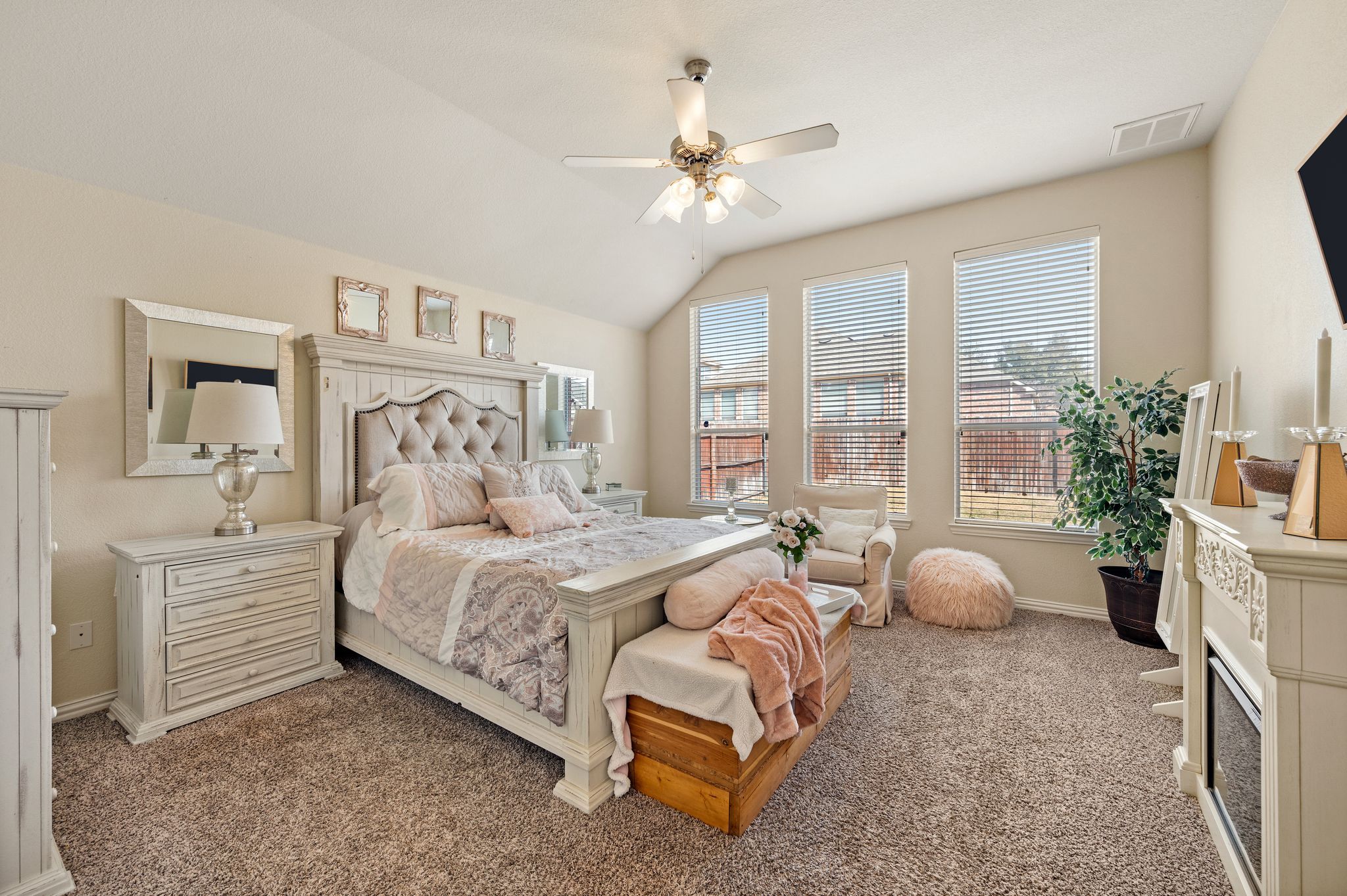 Spacious primary bedroom with vaulted ceilings, large windows, sitting area, and ensuite bath in a single-story home in Fort Worth, TX.