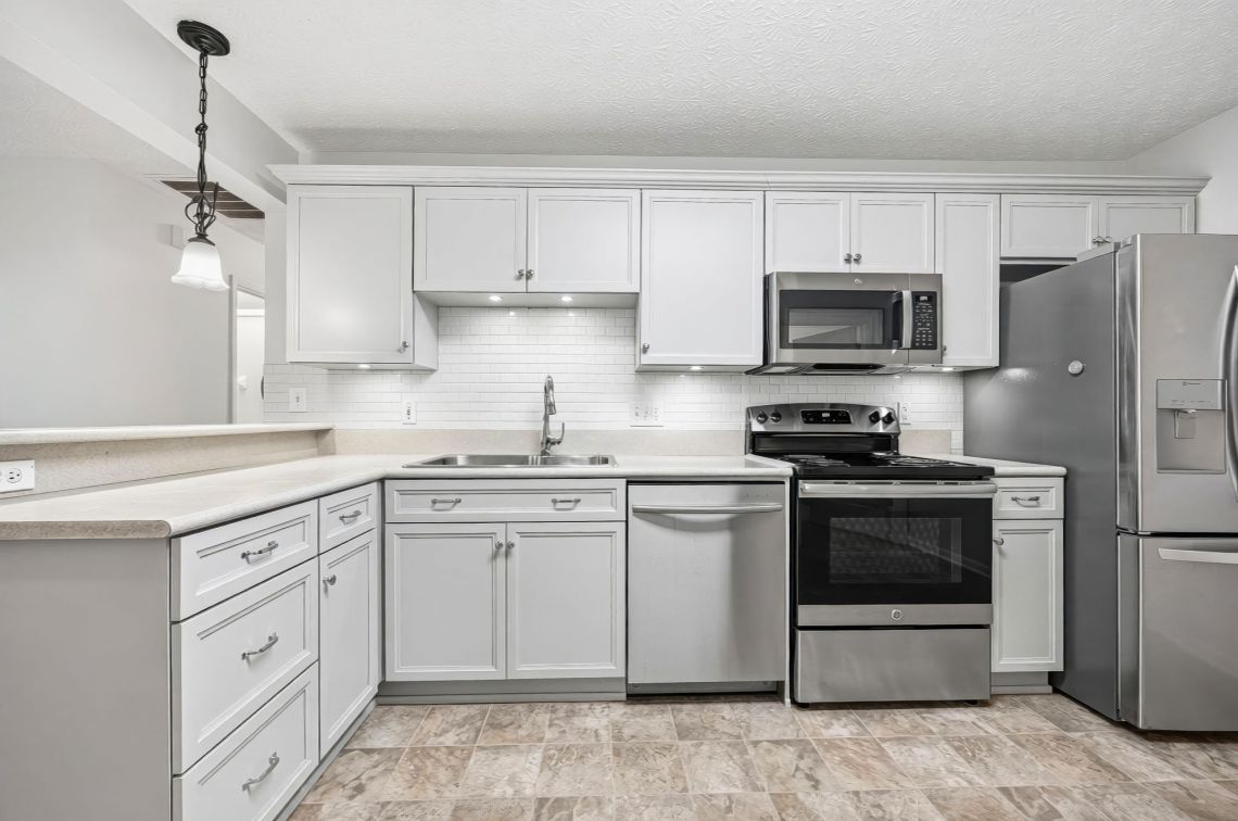 Kitchen with light gray cabinetry, subway tile, and undercabinet LEDs