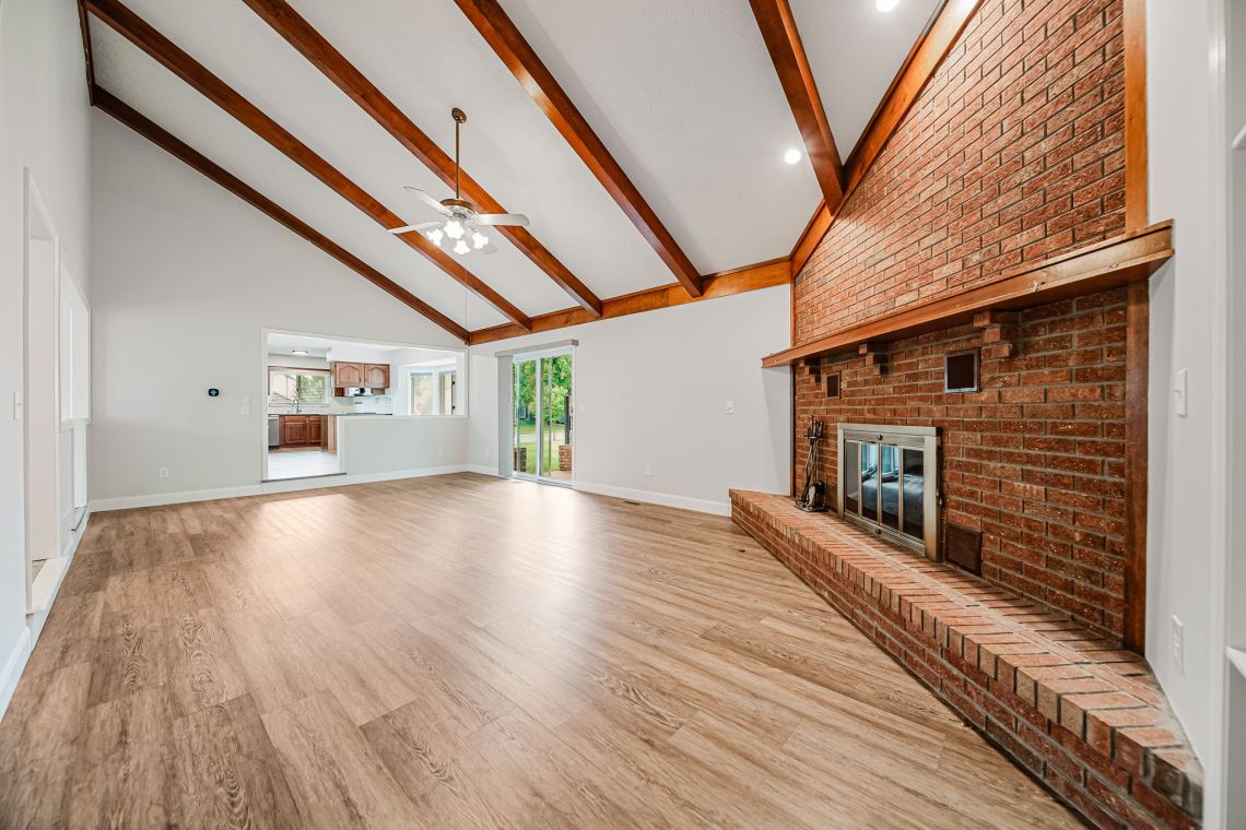 Vaulted great room with beams and brick fireplace