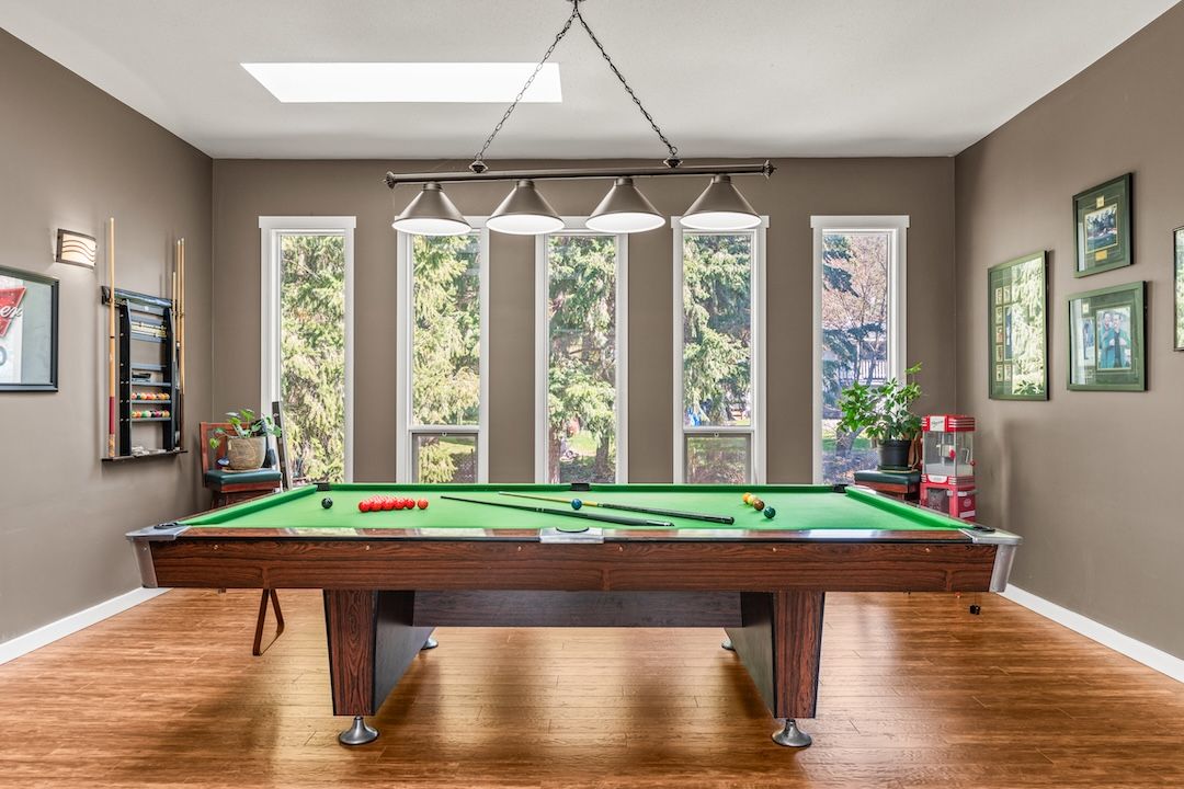 Pool table under a wall of tall windows