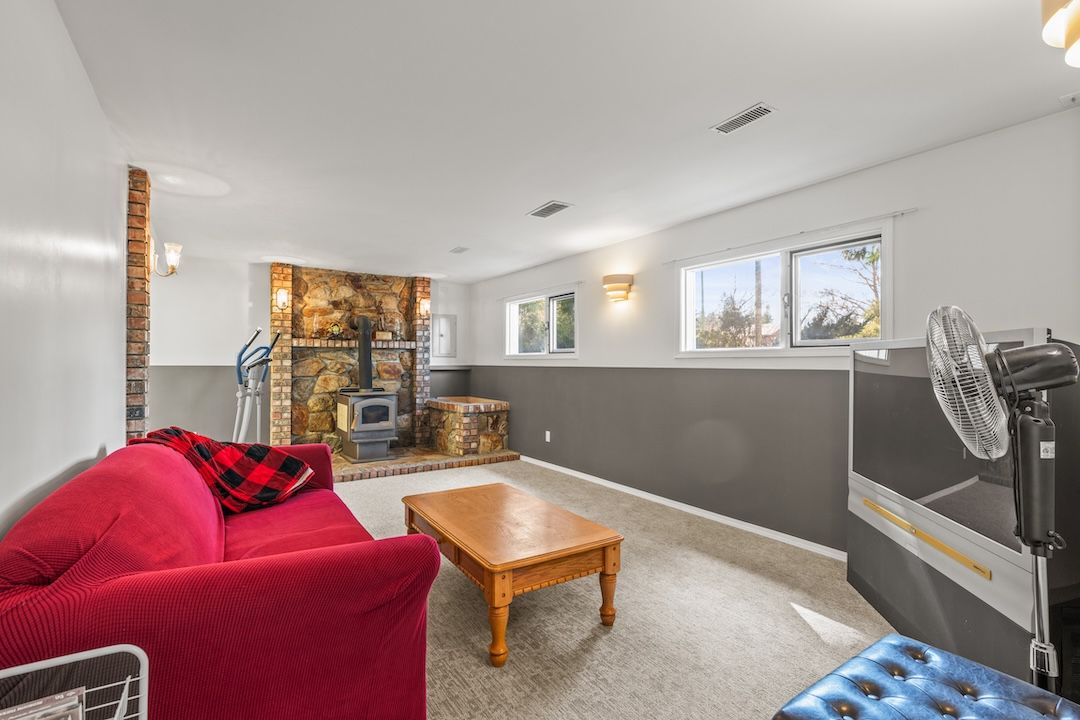 Lower-level family room with a wood stove on a stone hearth