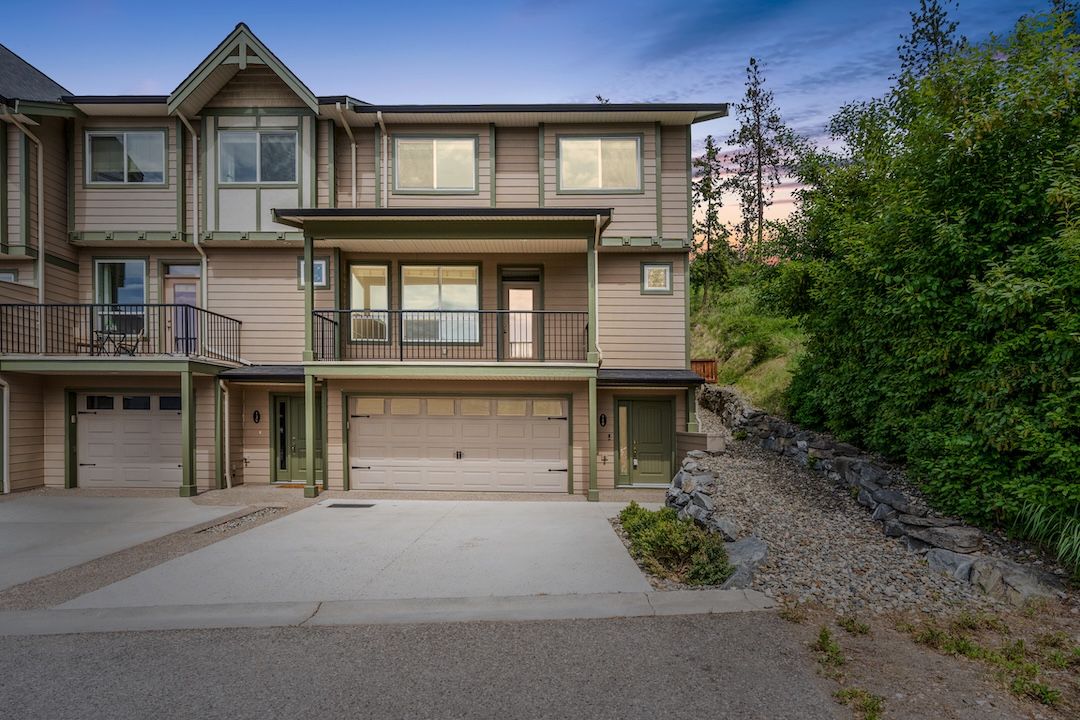 Front exterior of 140-3780 Schubert Road, an end-unit townhome at Willowbrook Terrace in Armstrong, BC with double attached garage and mountain views