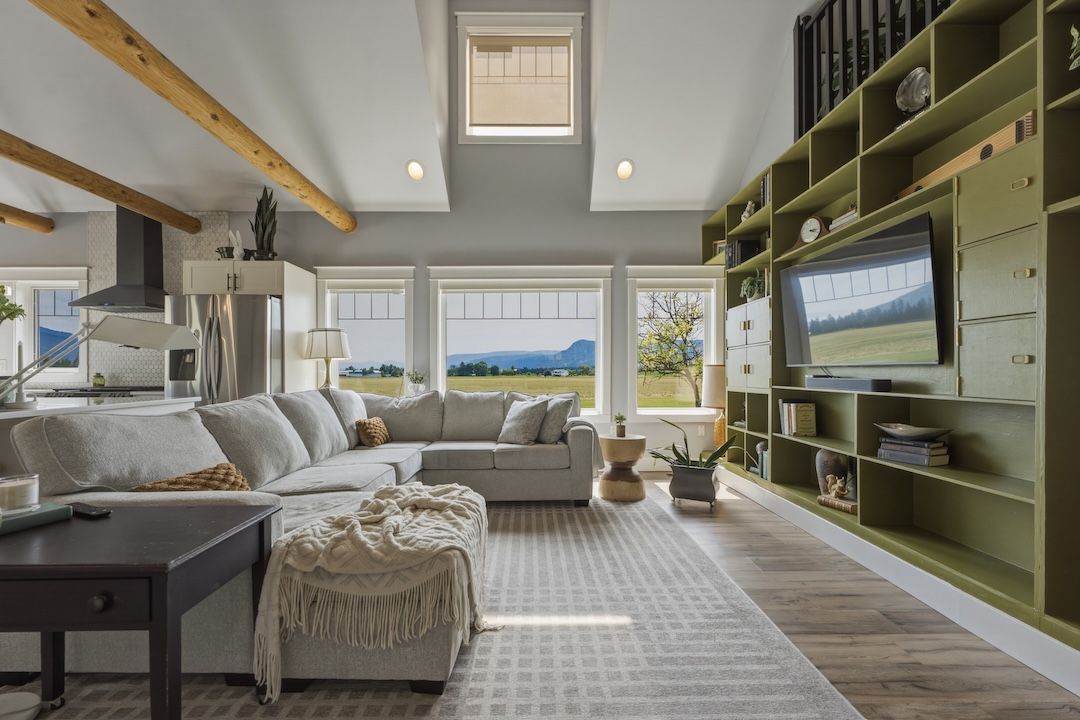 Great room with vaulted ceiling, exposed timber beams, and farmland views through large windows
