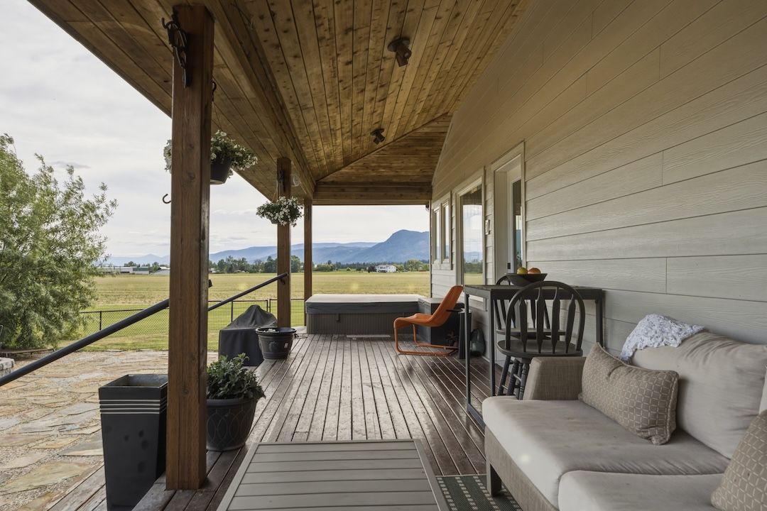 Covered wraparound veranda with seating and farmland views