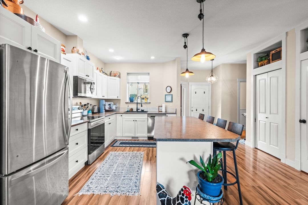 Open kitchen with a large butcher-block island, white cabinetry, and stainless appliances