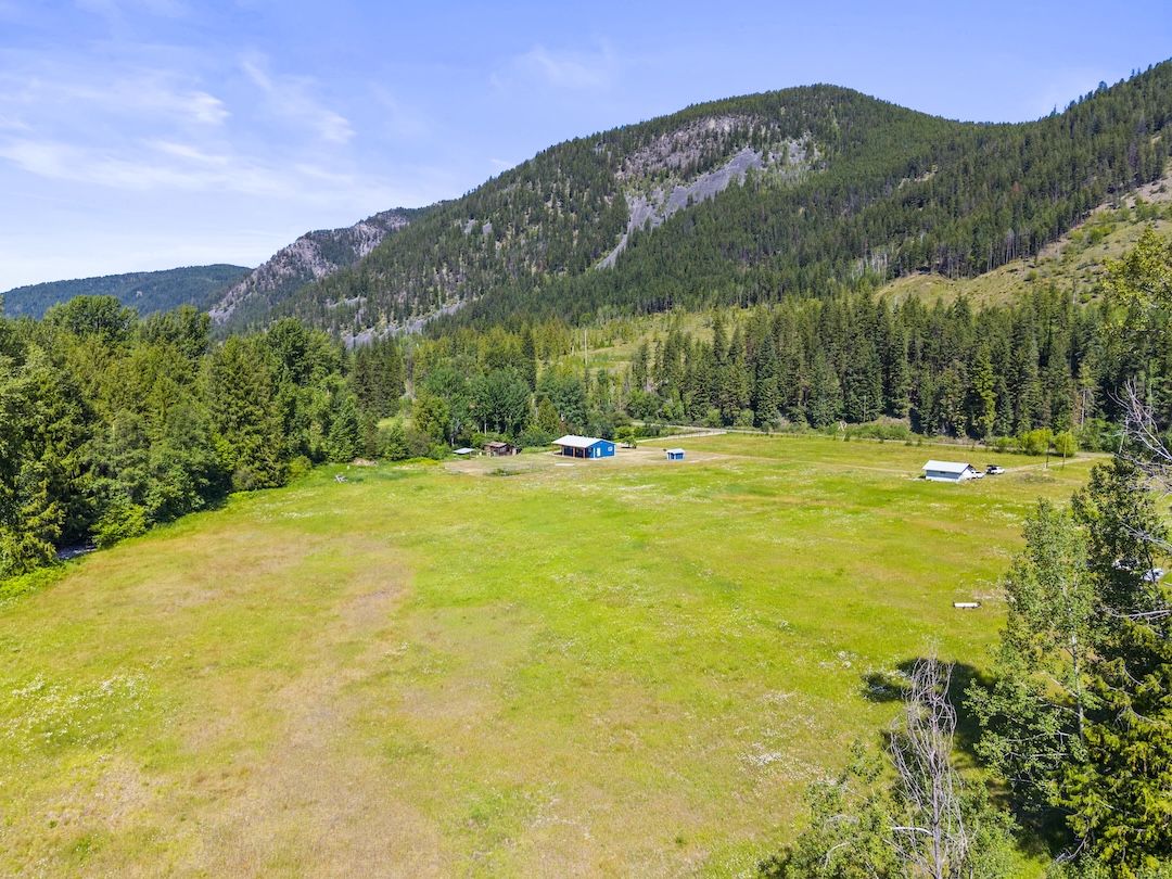 Aerial view of the home set into its acreage with mountains behind