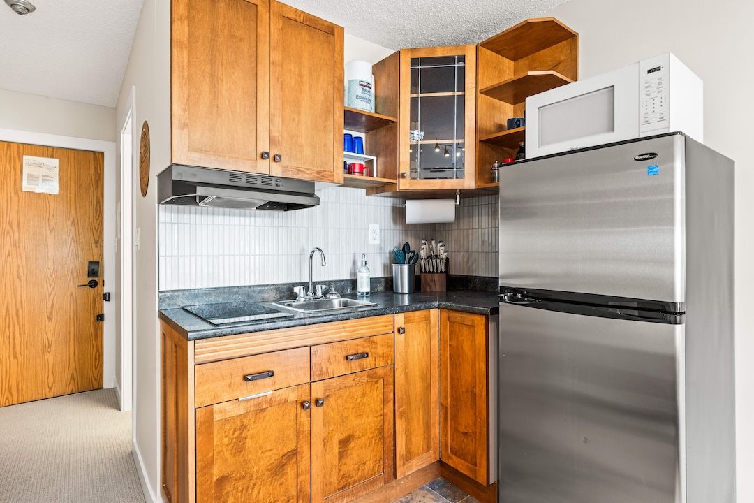 Kitchen with wood cabinets, microwave and stainless fridge