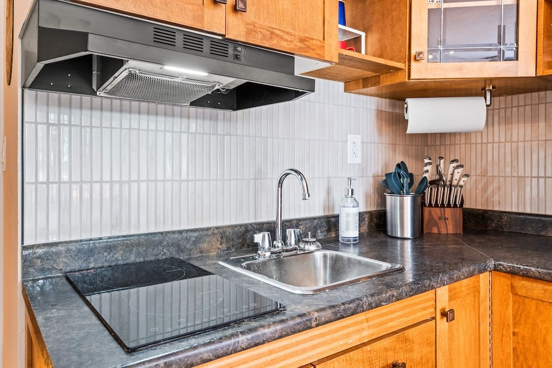 Renovated kitchen with tile backsplash and induction cooktop