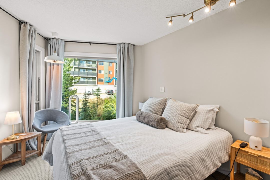 Bed with side tables, lamps and a chair by the window