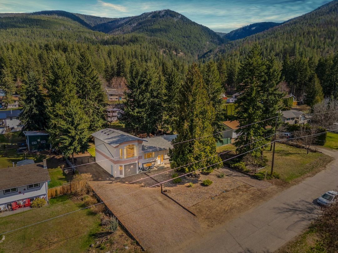 Aerial view of the home, parking and RV pad with the mountains behind