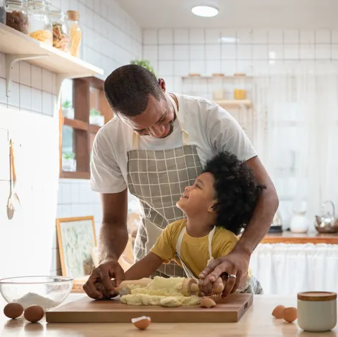 happy smiling african family  in aprons cooking and kneading dough on wooden table